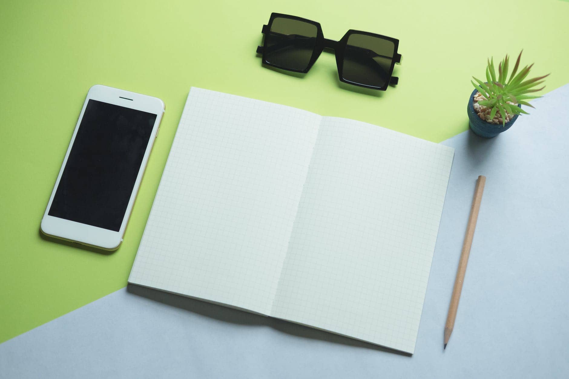 flat lay photography of smartphone printer paper sunglasses and pencil
